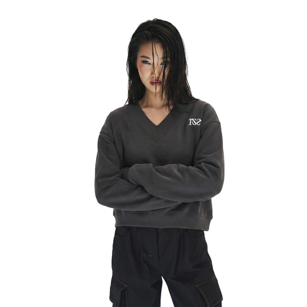 Person wearing a dark gray sweatshirt with a logo on a white background